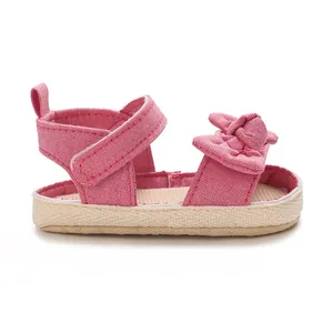 Detalle de sandalia de lona rosa para bebé niña con lazo y cierre de velcro.