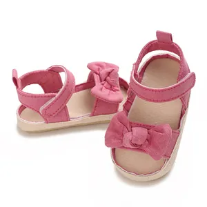 Primer plano de sandalias rosas para bebé niña con lazo decorativo y cierre de velcro ajustable
