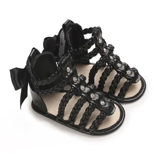 Schwarze Babysandalen mit geflochtenen Riemen, Strasssteinen und großer Schleife.