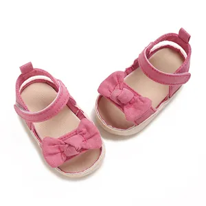 Detalle de sandalias de verano rosas para niñas con lazo grande de lona y punta abierta.