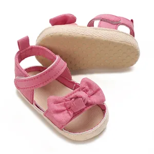 Detalle de sandalias rosas para bebé niña con un lazo lindo y suela antideslizante con textura