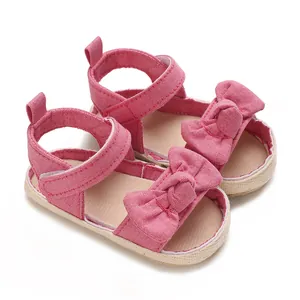 Primer plano de sandalias rosas para bebé niña con un lazo grande y suela antideslizante