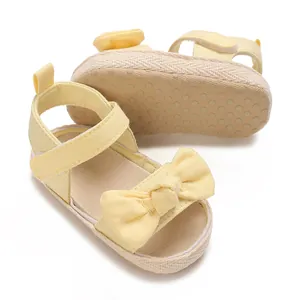 Detalle de sandalias amarillas de verano para bebé con lazo y suela antideslizante.