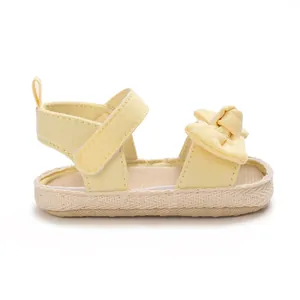 Vista lateral de sandalias amarillas de verano para bebé niña con lazo y cierre de velcro