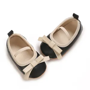Close-up detail of infant girl princess flats with black PU leather and beige bow ornament