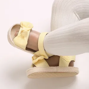 Detalle de sandalias amarillas para niña con lazo y diseño cómodo de punta abierta