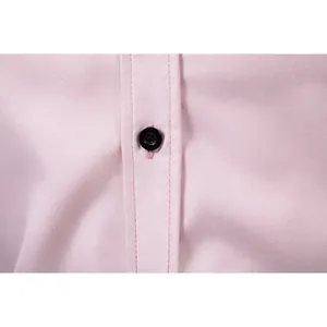 Detailed close-up of a black button and neat stitching on pink men's business shirt