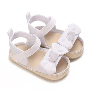 Detalle de sandalias blancas para bebé niña con lazo decorativo y cierre de velcro