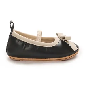Side view of a black baby girl princess shoe with a beige bow detail and soft sole