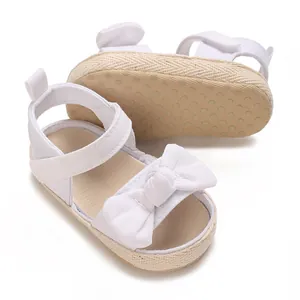 Primer plano de sandalias blancas para bebé con lazo y suela blanda antideslizante