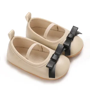 Close-up view of elegant cream baby girl sandals featuring a stylish black leather bow