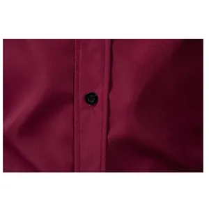 Close-up of black button and stitching on a burgundy business formal shirt for men.