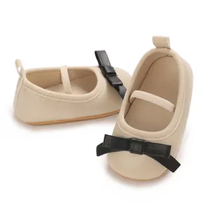 Detailed view of cream baby princess shoes with elegant black bow decoration