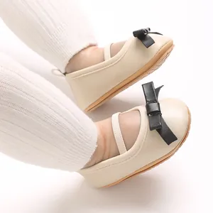 Detailed view of beige baby girl princess sandals with elegant black bow decoration