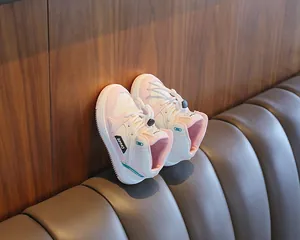 Detailed view of pink and white kids' high-top sports sneakers on a brown leather seat