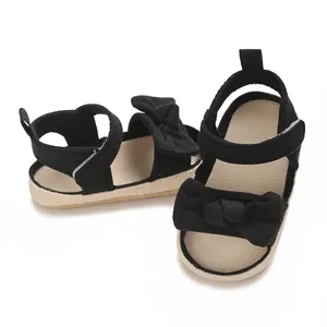 Detalle de sandalias negras para bebé niña con lazo grande y cierre de velcro