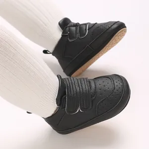 Nahaufnahme schwarzer Baby-Lauflernschuhe mit weicher Sohle und weißen Socken