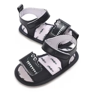 Close-up view of black baby sandals featuring a cute cartoon crocodile design and soft soles