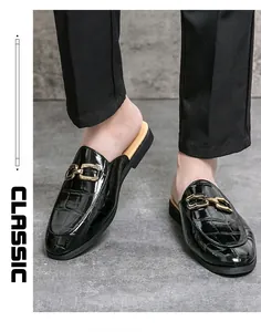 Detail of men's black glossy crocodile-embossed mules featuring elegant gold buckles