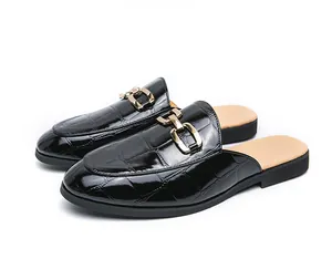 Close-up of men's black crocodile pattern mules with gold horsebit buckle