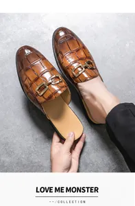 Men's brown crocodile-embossed leather mules with gold horsebit buckle detail.