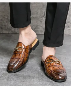 Detail view of men's brown crocodile embossed leather loafers with gold buckle