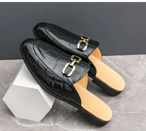 Macro detail showing the black crocodile texture and gold buckle of men's mules.