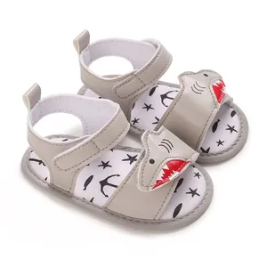 Close-up detail of grey baby sandals featuring cute cartoon shark and soft star print sole