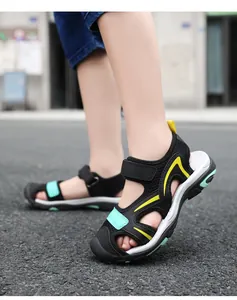 Close-up of breathable black closed-toe children's sandals on a paved outdoor road