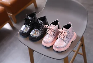 Bottines Martin brillantes pour enfants à motif de cœur en noir et rose sur chaise