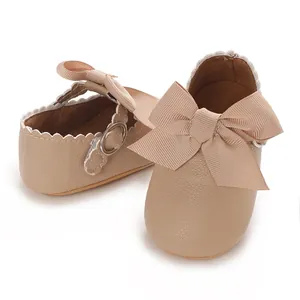 Détail de chaussures de princesse beige pour bébé fille avec un grand nœud côtelé