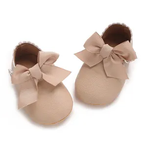 Gros plan de chaussures de bébé beiges avec un grand nœud en ruban et texture en cuir PU.