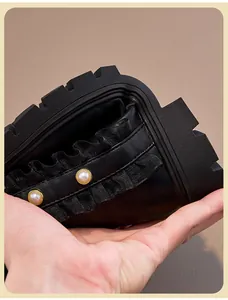 Detailed view of girls black Martin boots featuring elegant ruffles and pearl accents.