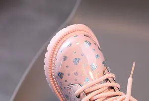 Vue rapprochée de bottines roses à paillettes pour enfants avec motifs cœurs