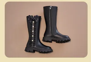 Detail view of black girls high-top boots with bow and pearl accents.