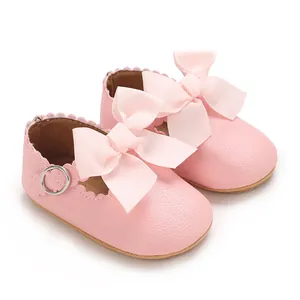 Gros plan de chaussures de princesse pour bébé en similicuir rose avec nœud et bords festonnés.