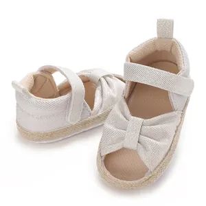 Close-up of soft-sole baby sandals with elegant bow detail and woven straw-textured trim.