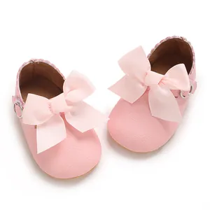 Vue détaillée des chaussures de princesse roses pour bébé avec de grands nœuds en ruban.