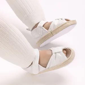 Close-up of elegant white baby sandals with espadrille trim and soft cloth sole.