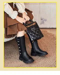 Detail of girls' black high-top boots with bow and pearl accents in a lifestyle setting.