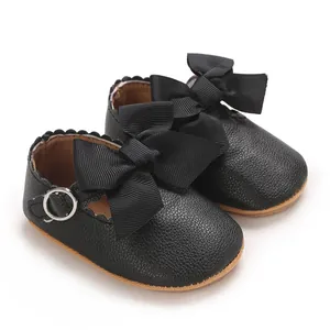 Vue détaillée de chaussures de princesse noires pour bébé avec de gros nœuds en ruban