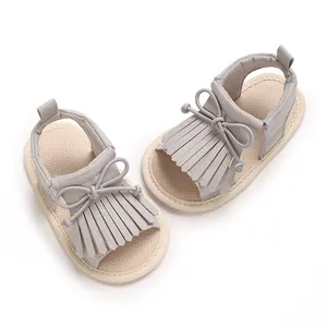Detailaufnahme von Babysandalen mit grauem Fransendesign und Schleife auf weicher Sohle.