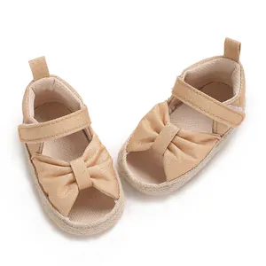 Close-up of champagne gold baby sandals with soft bow and velcro strap