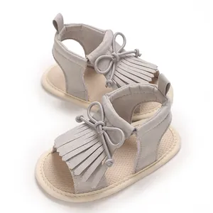 Detailansicht der grauen Lauflernsandalen für Babys mit Fransen und weicher Schleife.