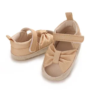 Close-up view showing the soft fabric sole and bow design of these gold baby sandals