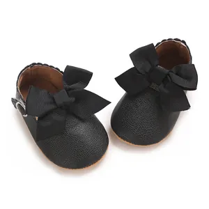 Gros plan de chaussures de princesse pour bébé en PU noir avec un grand nœud.