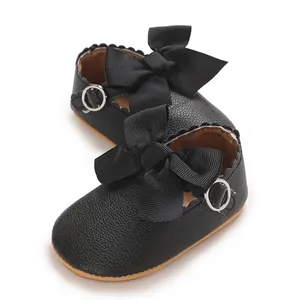 Gros plan sur des chaussures de princesse bébé noires avec nœuds en ruban et cuir PU.