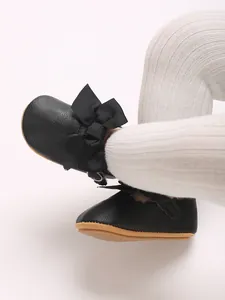 Detail view of black PU baby girl princess shoes featuring a large bow and soft sole