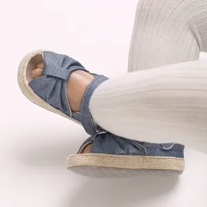 Close-up of soft-sole baby sandals featuring blue denim fabric and woven rope edge