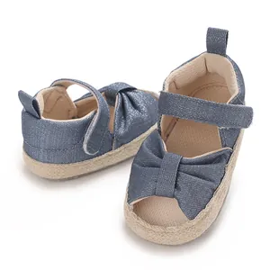 Close-up detail of blue glitter denim baby sandals featuring a bow and woven sole.
